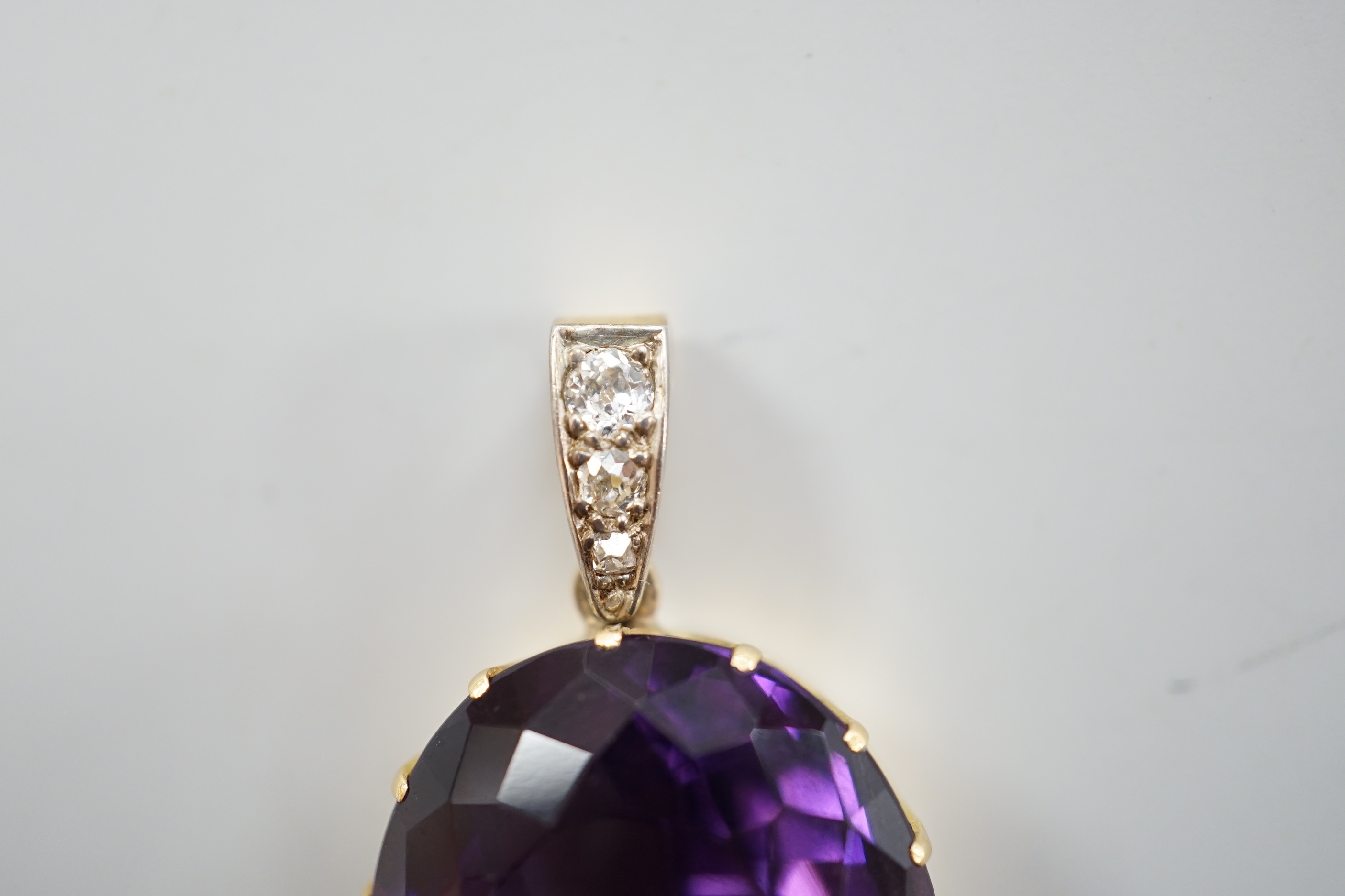 An Edwardian yellow metal, oval cut amethyst and three stone diamond set drop pendant, overall 4cm, gross weight 16.7 grams.